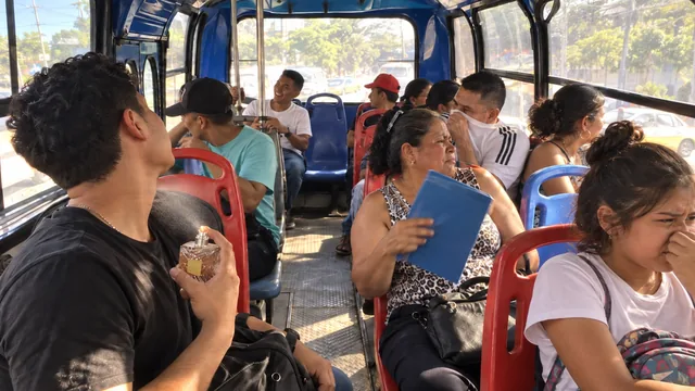 Pasajeros de una buseta de Barranquilla tapándose la nariz mientras un joven sostiene un frasco de perfume